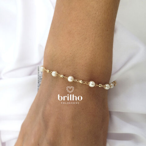 Foto braço de modelo de pele clara usando pulseira Infantil pérola e bola dourada da marca Rommanel revendida pela Brilho folheados. Código 550883