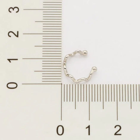 fundo cinza com uma régua na cor preta e um pouquinho acima um brinco piercing na cor prata com o formato ondulado