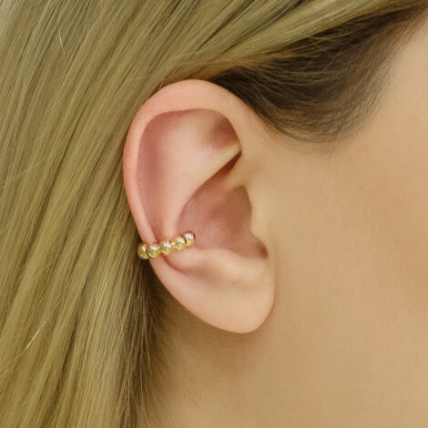 Foto orelha de modelo de pele clara, usando o brinco piercing de pressão bolinhas folhado a ouro 18k. Código 1690553