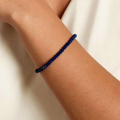 Foto com imagem no pulso de uma mulher de pele clara usando a pulseira de cristais azul facetados da marca Rommanel.