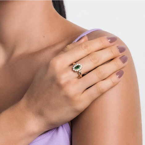 Foto de modelo de pele clara, colocando a mão no ombro usando o anel formatura com cristal verde e zircônias. Código 513285