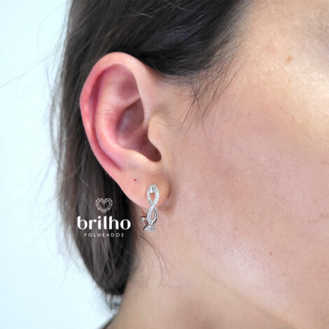 Foto orelha de modelo de pele clara usando brinco argola entrelaçada pequena com zircônias folheado a Ródio. Código R1690894 