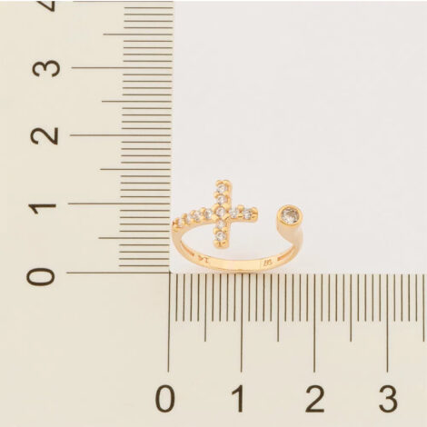 Foto com imagem de régua medindo o anel ajustável cruz com zircônias brancas banhado a ouro, cor dourado. Código 513262