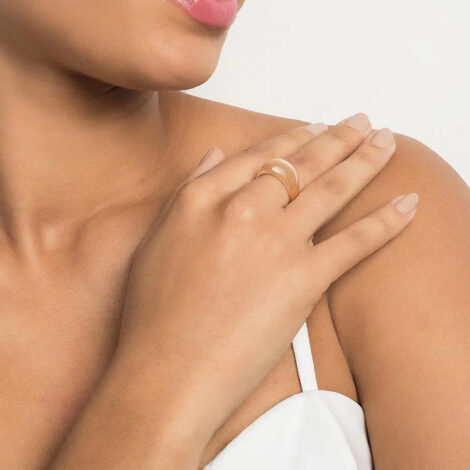 Foto de modelo de pele clara com a mão no ombro usando o anel abaulado prosperidade com escrita folheado a ouro, cor dourado. Código 513318