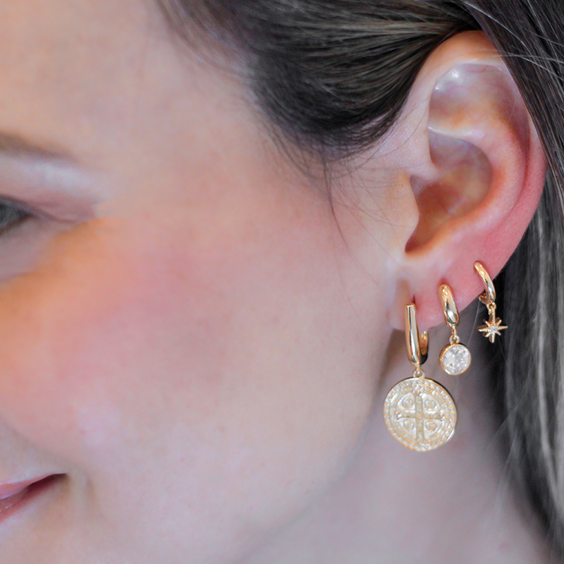 Foto de modelo de pele clara usando na orelha o brinco mini argola com cristal folheado a ouro 18k, da marca Sabrina Joias revendido pela loja Brilho Folheados. Código 1690680